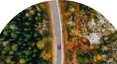 Footage of a red car driving down the highway surrounded by trees
