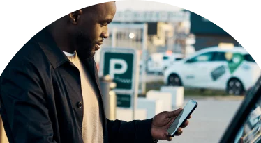 A man adding gas to their car while staring at their phone