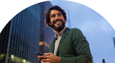 A bearded man smiling while holding their phone